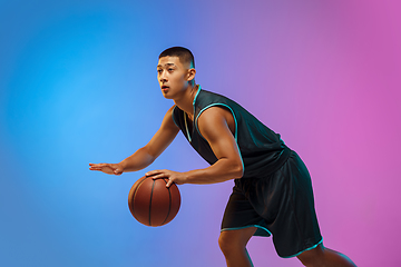 Image showing Young basketball player in motion on gradient studio background in neon light
