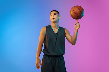 Image showing Young basketball player in motion on gradient studio background in neon light