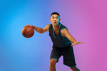 Image showing Young basketball player in motion on gradient studio background in neon light