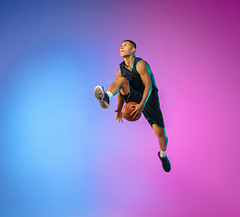 Image showing Young basketball player in motion on gradient studio background in neon light