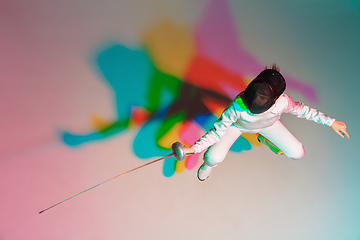 Image showing Teen girl in fencing costume with sword in hand on gradient background with neon light, top view