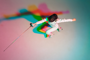 Image showing Teen girl in fencing costume with sword in hand on gradient background with neon light, top view