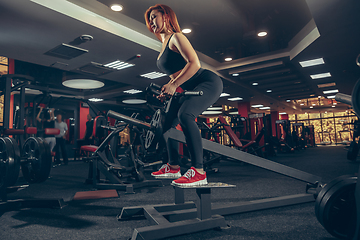 Image showing Young muscular caucasian woman practicing in gym with equipment. Wellness, healthy lifestyle, bodybuilding.