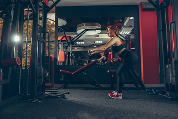 Image showing Young muscular caucasian woman practicing in gym with equipment. Wellness, healthy lifestyle, bodybuilding.