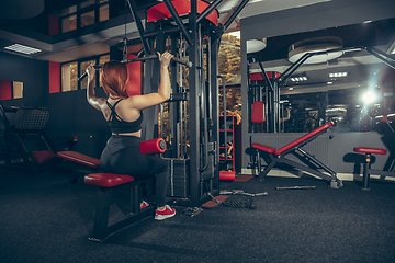 Image showing Young muscular caucasian woman practicing in gym with equipment. Wellness, healthy lifestyle, bodybuilding.