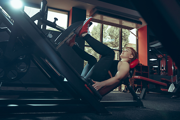 Image showing Young muscular caucasian woman practicing in gym with equipment. Wellness, healthy lifestyle, bodybuilding.