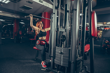 Image showing Young muscular caucasian woman practicing in gym with equipment. Wellness, healthy lifestyle, bodybuilding.