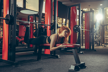 Image showing Young muscular caucasian woman practicing in gym with equipment. Wellness, healthy lifestyle, bodybuilding.