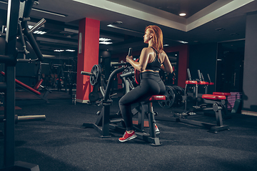 Image showing Young muscular caucasian woman practicing in gym with equipment. Wellness, healthy lifestyle, bodybuilding.