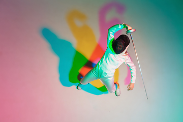 Image showing Teen girl in fencing costume with sword in hand on gradient background with neon light, top view