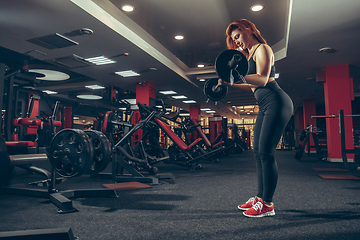 Image showing Young muscular caucasian woman practicing in gym with equipment. Wellness, healthy lifestyle, bodybuilding.