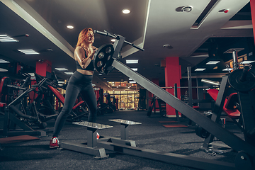 Image showing Young muscular caucasian woman practicing in gym with equipment. Wellness, healthy lifestyle, bodybuilding.