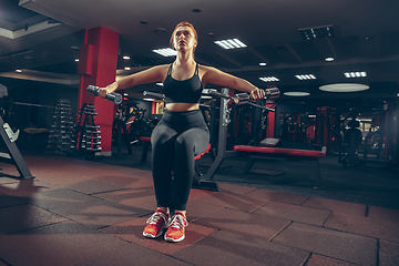 Image showing Young muscular caucasian woman practicing in gym with equipment. Wellness, healthy lifestyle, bodybuilding.