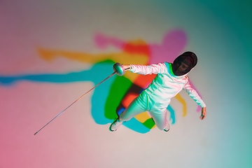 Image showing Teen girl in fencing costume with sword in hand on gradient background with neon light, top view