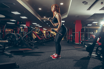 Image showing Young muscular caucasian woman practicing in gym with equipment. Wellness, healthy lifestyle, bodybuilding.