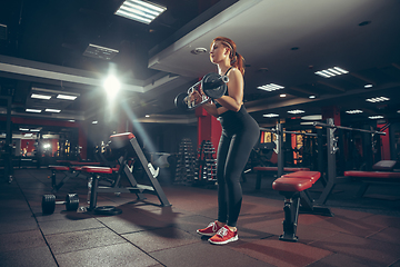 Image showing Young muscular caucasian woman practicing in gym with equipment. Wellness, healthy lifestyle, bodybuilding.