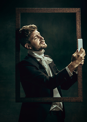 Image showing Young man as Dorian Gray on dark background. Retro style, comparison of eras concept.