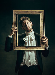 Image showing Young man as Dorian Gray on dark background. Retro style, comparison of eras concept.