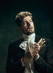 Image showing Young man as Dorian Gray on dark background. Retro style, comparison of eras concept.