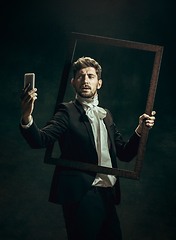 Image showing Young man as Dorian Gray on dark background. Retro style, comparison of eras concept.