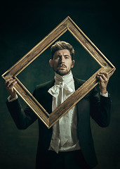 Image showing Young man as Dorian Gray on dark background. Retro style, comparison of eras concept.