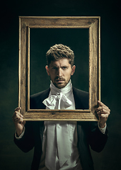 Image showing Young man as Dorian Gray on dark background. Retro style, comparison of eras concept.