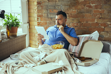 Image showing Lazy man living the whole life in his bed surrounded with messy