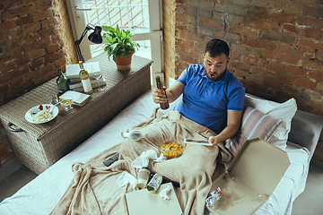 Image showing Lazy man living the whole life in his bed surrounded with messy
