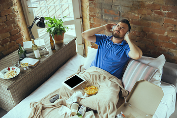 Image showing Lazy man living the whole life in his bed surrounded with messy