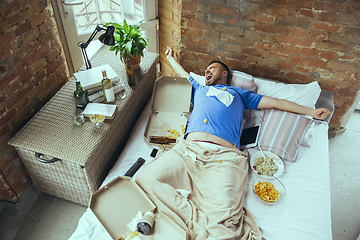 Image showing Lazy man living the whole life in his bed surrounded with messy