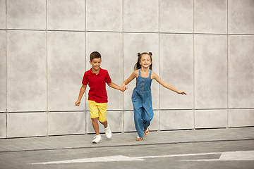 Image showing Two smiling kids, boy and girl running together in town, city in summer day