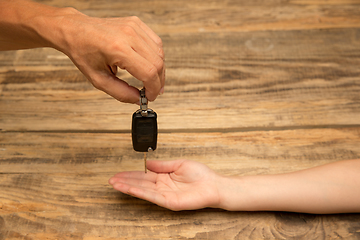 Image showing Human hands holding car key isolated on wooden background with copyspace