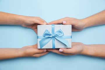 Image showing Human\'s hands holding a present, gift, surprise box isolated on blue background