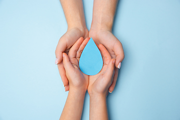 Image showing Human hands holding water drop isolated on white wooden background