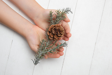 Image showing Human\'s hand holding a Christmas decoration isolated on white wooden background