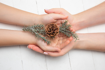 Image showing Human\'s hand holding a Christmas decoration isolated on white wooden background