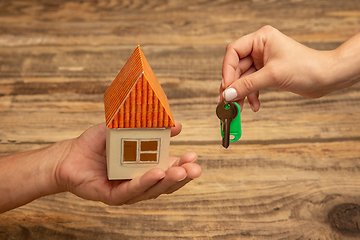 Image showing Real estate and eco concept - close up picture of human hands holding house on wooden background