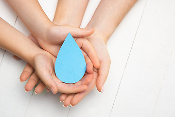 Image showing Human hands holding water drop isolated on white wooden background
