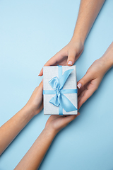 Image showing Human\'s hands holding a present, gift, surprise box isolated on blue background