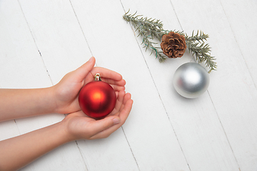 Image showing Human\'s hand holding a Christmas ball isolated on wooden white background