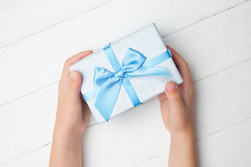 Image showing Human\'s hands holding a present, gift, surprise box isolated on white wooden background