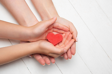 Image showing Human hands holding, giving heart isolated on white wooden background