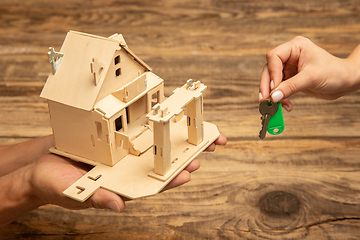 Image showing Real estate and eco concept - close up picture of human hands holding house on wooden background