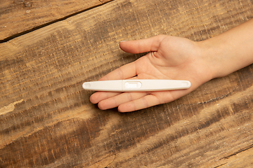 Image showing Human hand holding thermometer isolated on wooden background