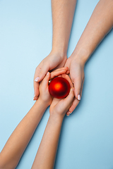 Image showing Human\'s hand holding a Christmas ball isolated on blue background