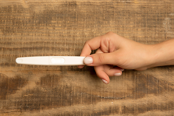 Image showing Human hand holding thermometer isolated on wooden background