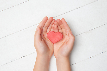 Image showing Human hands holding, giving heart isolated on white wooden background