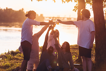 Image showing Group of friends clinking beer glasses during picnic at the beach. Lifestyle, friendship, having fun, weekend and resting concept.