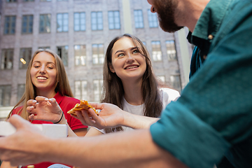 Image showing Tourists, friends enjoying pizza on street and smiling. Summertime, fast food