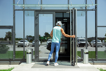 Image showing Sports man against modern glassed building, airport in megapolis